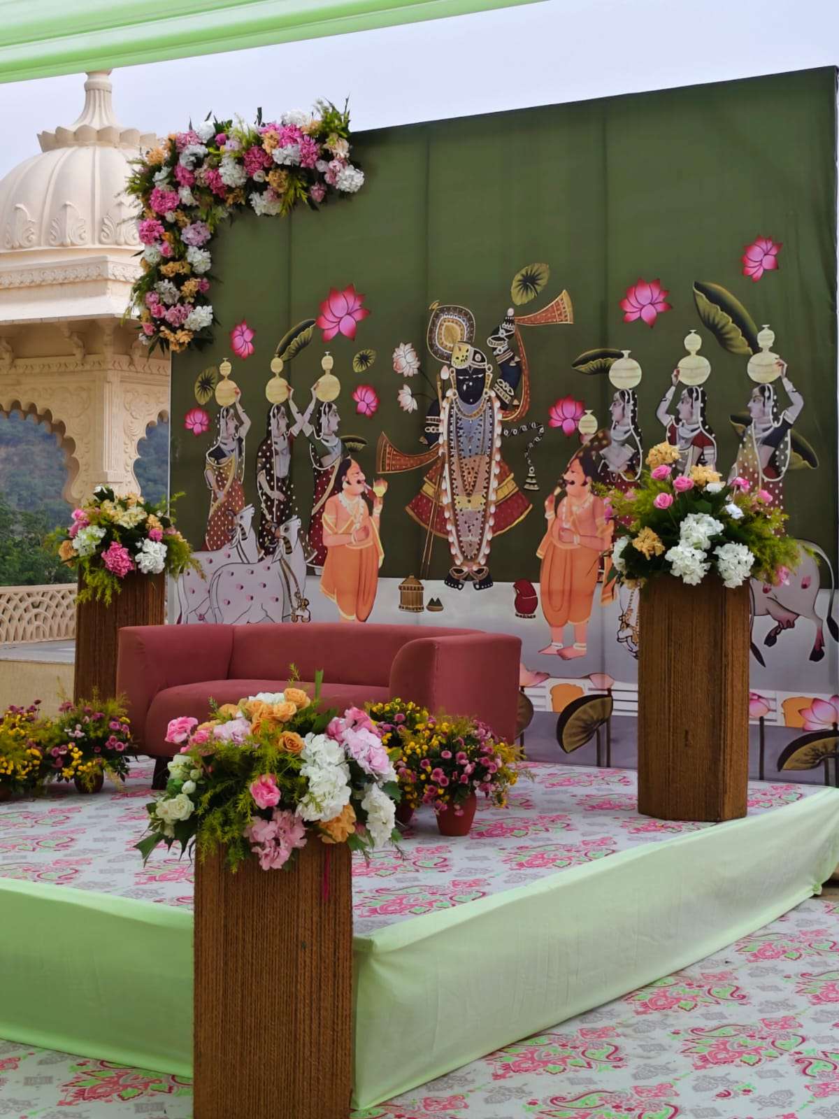 Wedding stage with Shrinathji painting backdrop and pink floral columns